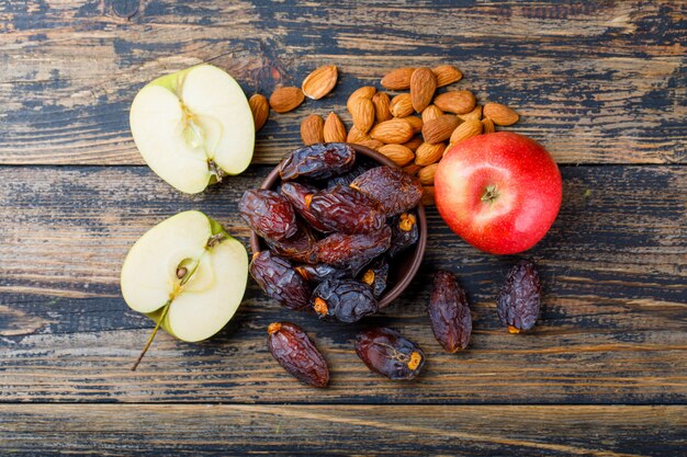 Manzana y mitades con fechas en tazón y almendras en madera vieja