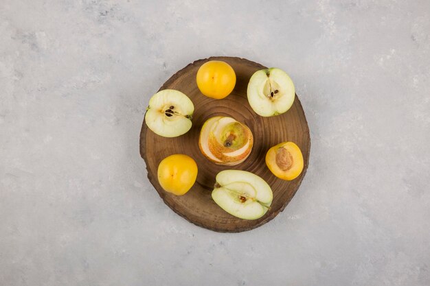 Manzana, pera y melocotones en un trozo de madera en el medio