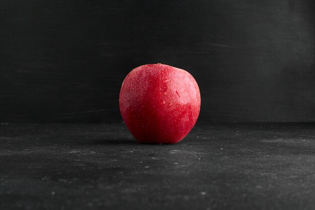 Una manzana roja aislada en superficie negra.