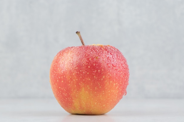 Manzana roja con gotas de agua sobre la mesa de piedra.