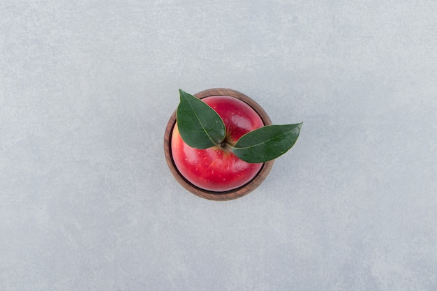 Manzana roja con hojas en tazón de madera