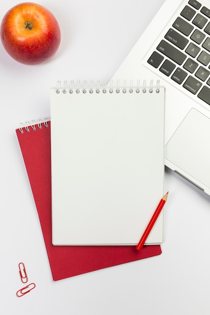 Foto gratuita manzana roja, libreta espiral en blanco, lápiz de color rojo en la computadora portátil sobre fondo blanco