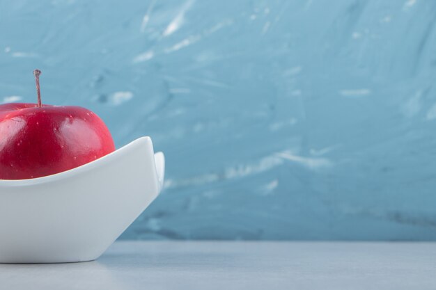 Manzana roja madura en tazón de fuente blanco