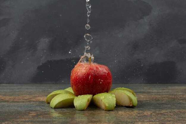 Manzana roja con rodajas de manzana sobre la superficie de mármol.