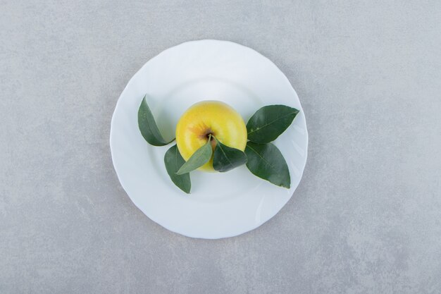 Foto gratuita manzana sola con hojas en un plato blanco.