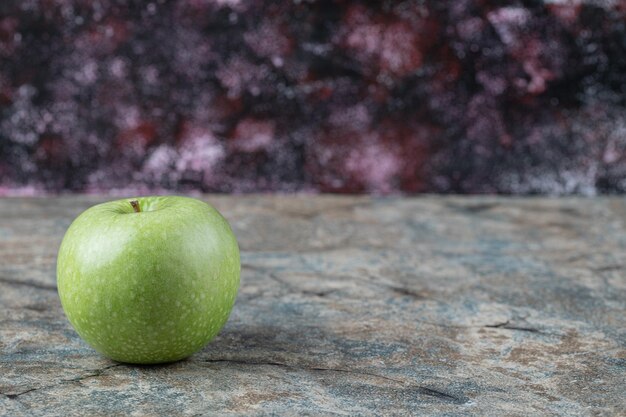 Manzana verde aislada sobre hormigón.