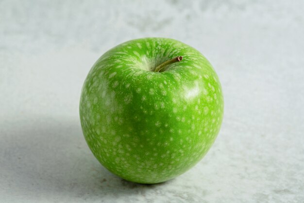 Una manzana verde fresca orgánica. Sobre superficie gris.