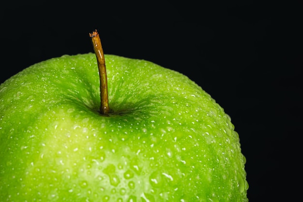 Foto gratuita manzana verde en gotas de agua sobre un fondo negro aislado