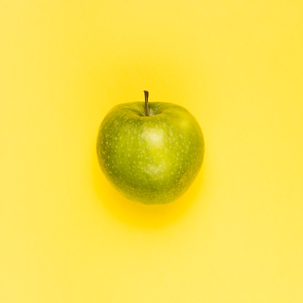 Manzana verde jugosa madura en superficie amarilla