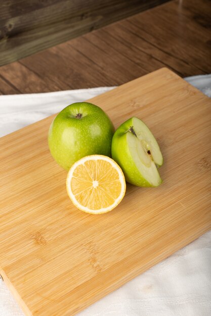 Manzana verde con limón fresco sobre una plancha de madera. vista superior