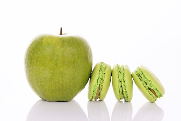 Manzana verde con macarrones sobre fondo blanco.