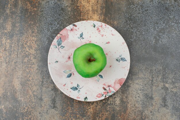Una manzana verde pelada en un hermoso plato sobre la superficie de mármol.