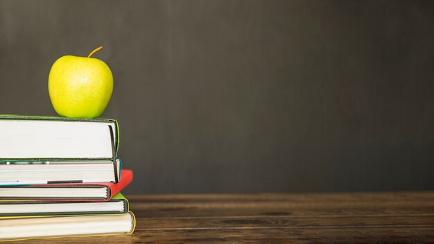 Manzana verde en la pila de libros en el escritorio