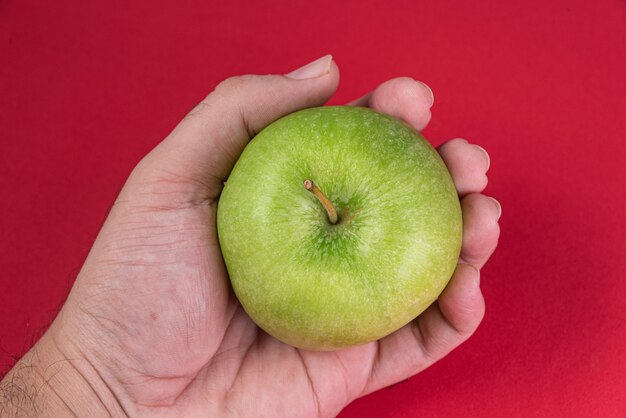 Manzana verde sobre fondo rojo - hombre sujetando