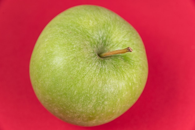 Manzana verde sobre fondo rojo.