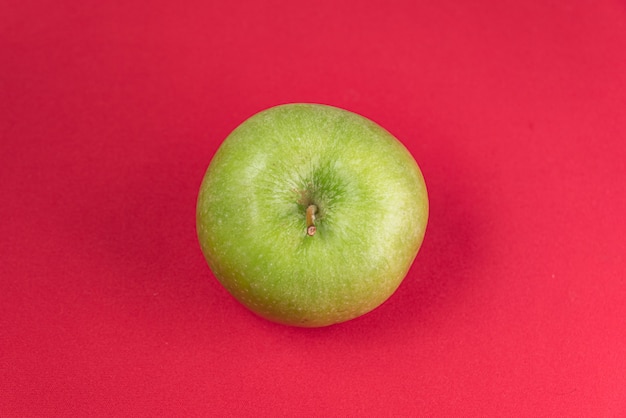 Manzana verde sobre fondo rojo.