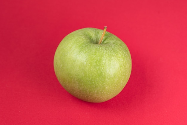 Manzana verde sobre rojo