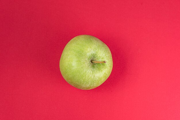 Manzana verde sobre rojo