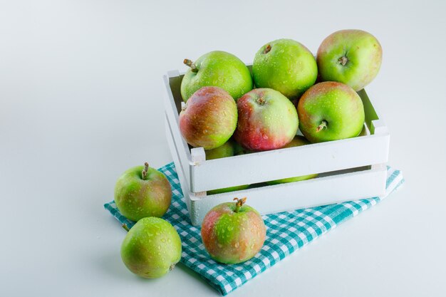 Manzanas en una caja de madera sobre tela blanca y picnic. vista de ángulo alto.