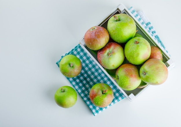 Manzanas en una caja de madera sobre tela blanca y picnic.