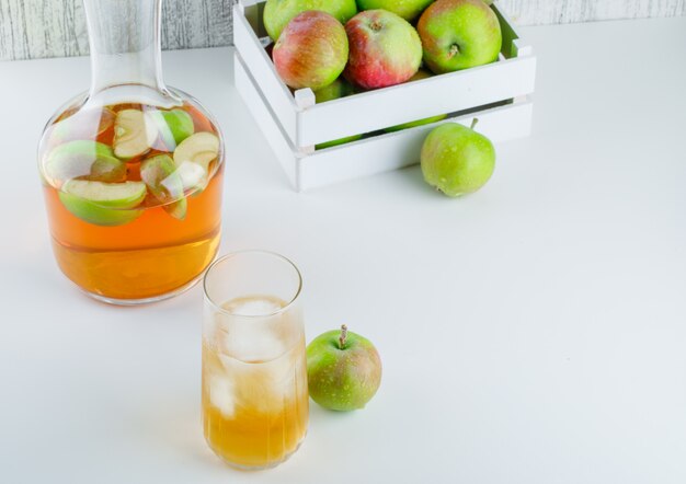 Manzanas en una caja de madera con vista de ángulo alto de bebida en blanco y sucio
