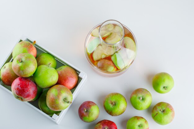 Manzanas en una caja de madera con vista superior de jugo en blanco