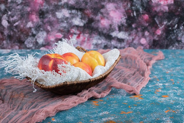 Manzanas en canasta de madera sobre arpillera blanca.