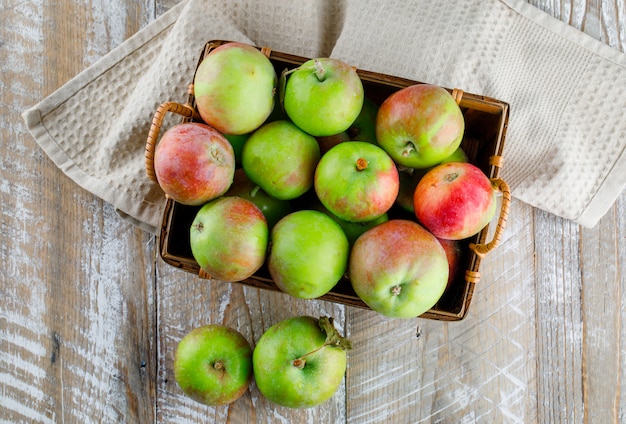 Manzanas en una canasta de madera y toalla de cocina