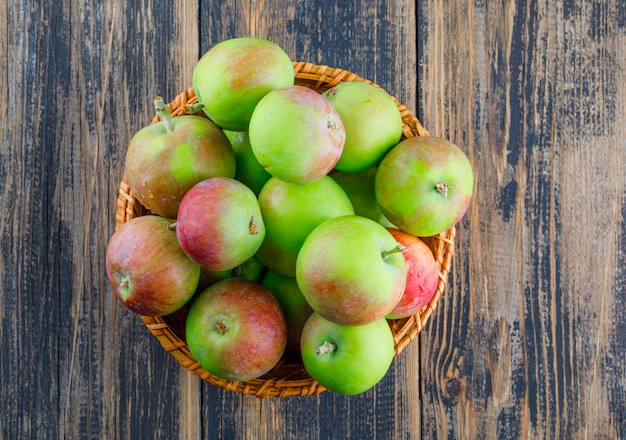 Manzanas en una canasta de mimbre sobre un fondo de madera. endecha plana.