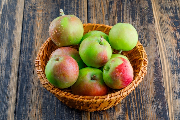 Manzanas en una canasta de mimbre sobre un fondo de madera. vista de ángulo alto.