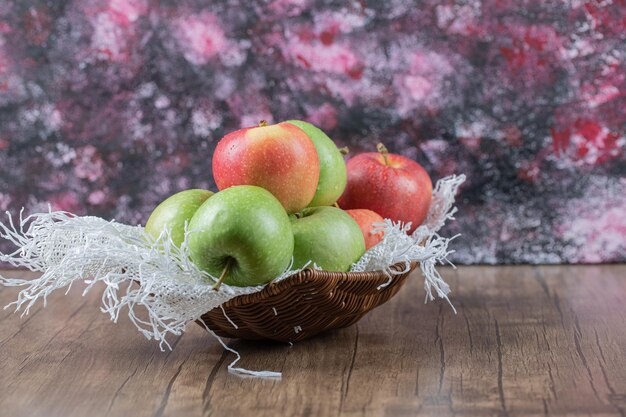 Manzanas en canasta sobre un trozo de arpillera blanca.