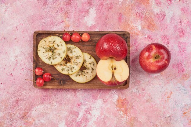 Manzanas y cerezas sobre tabla de madera.