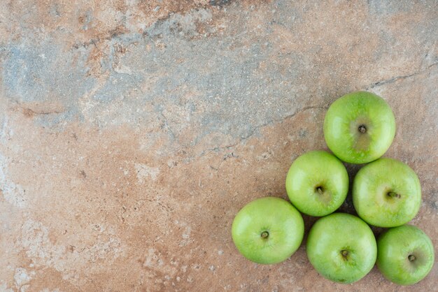 Manzanas dulces frescas verdes sobre mesa de mármol.