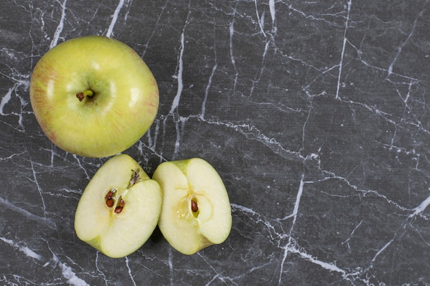 Manzanas enteras y en rodajas sobre mármol.