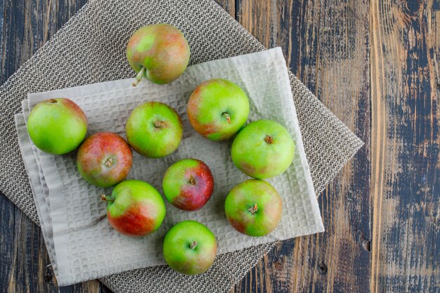 Manzanas esparcidas con toalla de cocina sobre fondo de madera y mantel, plano.