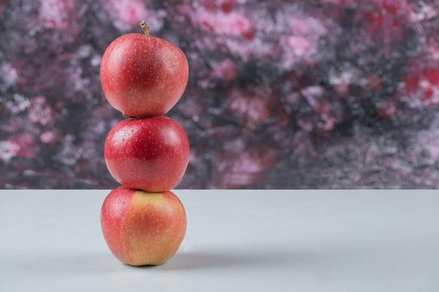 Manzanas en una fila aisladas sobre una mesa blanca.