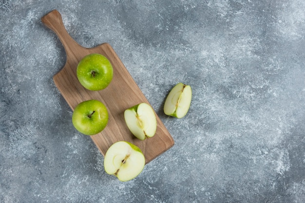 Manzanas frescas enteras y en rodajas sobre tabla de madera.