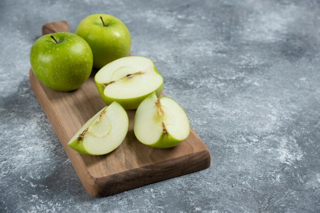 Manzanas frescas enteras y en rodajas sobre tabla de madera.