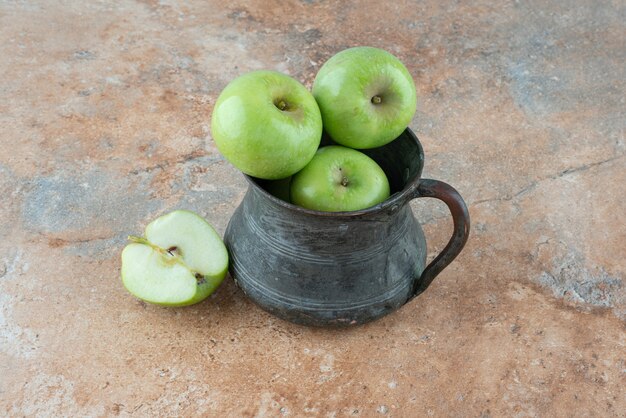 Manzanas frescas con una taza antigua sobre mesa de mármol.