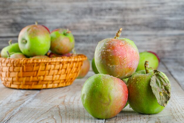 Manzanas frías en una cesta de mimbre sobre madera. vista lateral.