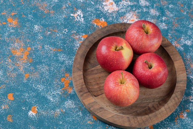 Manzanas jugosas en placa de madera redonda.