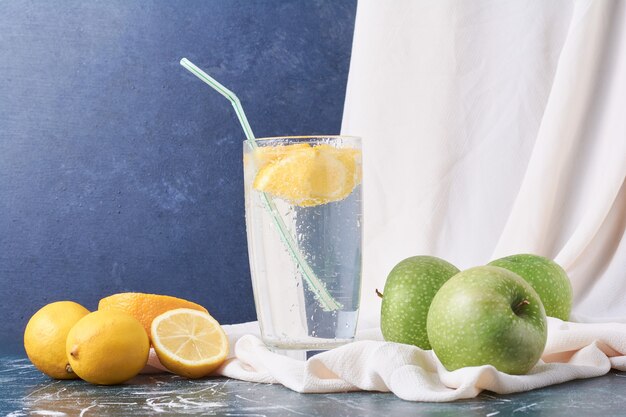 Manzanas de limón con una taza de bebida en azul.