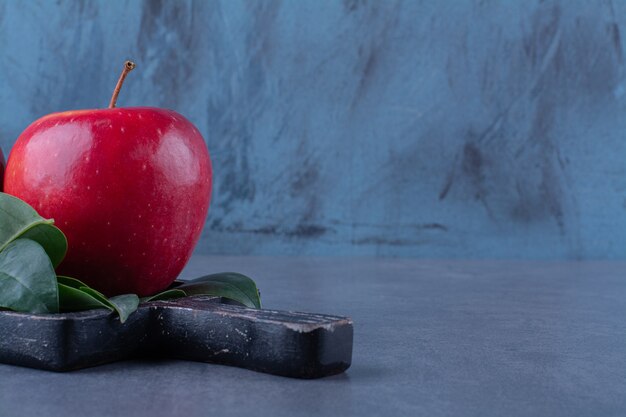 Manzanas maduras con hojas a bordo sobre mesa de mármol.