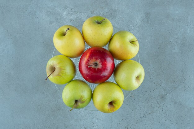Manzanas maduras sobre un pedestal de vidrio, sobre el fondo de mármol. Foto de alta calidad