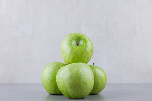 Manzanas maduras verdes frescas colocadas sobre una mesa de piedra.