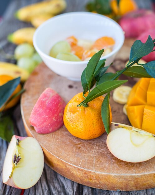 Manzanas mandarinas plátanos mangos y uvas en una tabla de madera