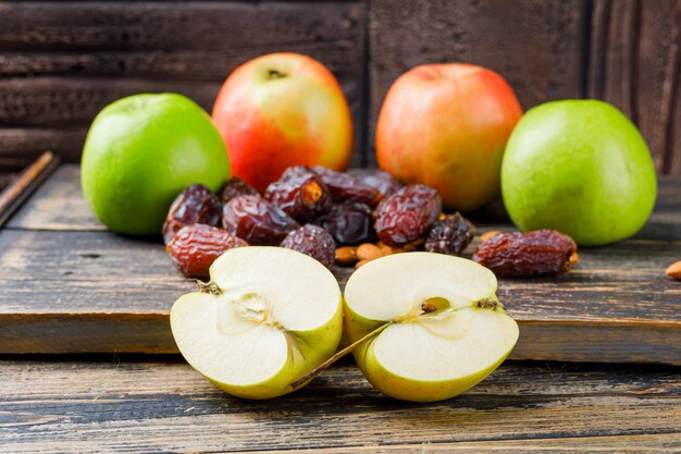 Manzanas y mitades con fechas y almendras en vista lateral de tablero de madera en baldosas de piedra y madera