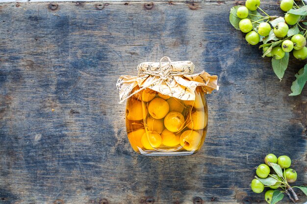 Manzanas del paraíso en jarabe de azúcar sobre una superficie de madera vieja