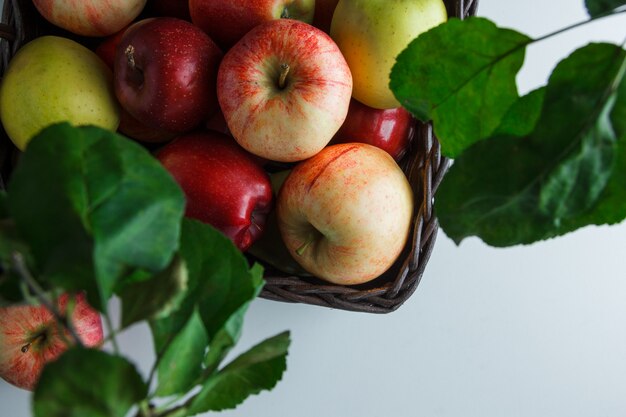 Manzanas planas en caja con hojas sobre fondo blanco. espacio horizontal para texto