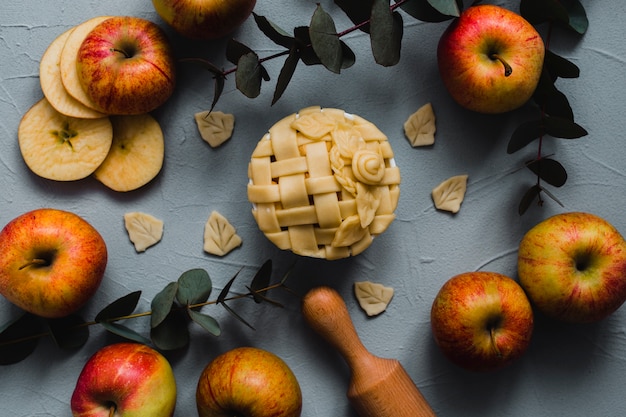 Foto gratuita manzanas y ramitas cerca de pastel y rodillo